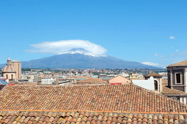 Verbazingwekkende Cityscape van Siciliaanse Catania, Italië met daken van historische gebouwen in de oude stad en de majestueuze Etna vulkaan op de achtergrond. Sneeuw op de top van de berg. Zonnige dag — Stockfoto