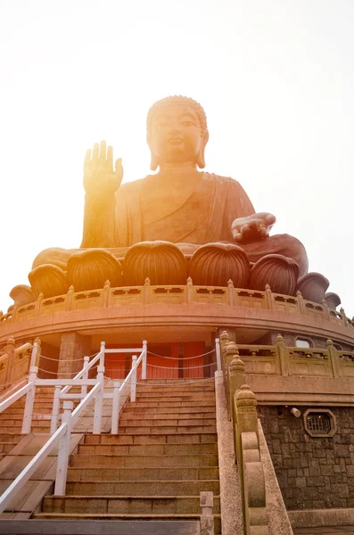 The enormous Tian Tan Buddha at Po Lin Monastery in Lantau Island, Hong Kong. Photographed during sunset with orange sun shining behind the statue. Popular tourist attraction