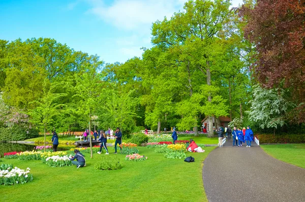Keukenhof, Lisse, Netherlands - Apr 28th 2019: People walking in beautiful Keukenhof gardens. Popular tourist park with green trees and colorful flowers, mainly tulips. Major Dutch tourist attraction — Stock Photo, Image