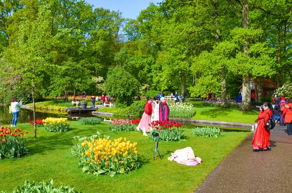 Keukenhof, Lisse, Netherlands - Apr 28th 2019: Asian tourist taking travel pictures in beautiful spring Keukenhof gardens. Dutch park with green trees and colorful tulips. Tourist place in Holland — Stock Photo, Image