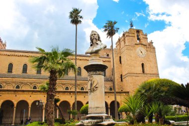 Monreale, Sicilya, İtalya - Nis 11th 2019: Monreale Tarihi Katedrali, Ressam Pietro Novelli büstü ile Duomo di Monreale dış. Palmiye ağaçları, bulutlu bir gün. Norman mimarisi