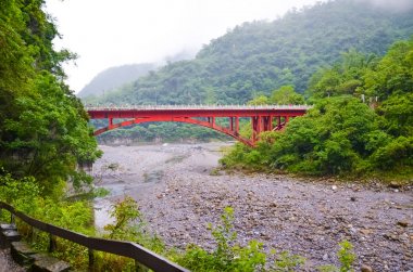 Taroko Ulusal Parkı, Tayvan nehir üzerinde kırmızı köprü görünümü. Taroko Gorge tropikal yeşil orman ve kayalar ile çevrilidir. Sisli siste fotoğraflandı. Yağmurlu hava