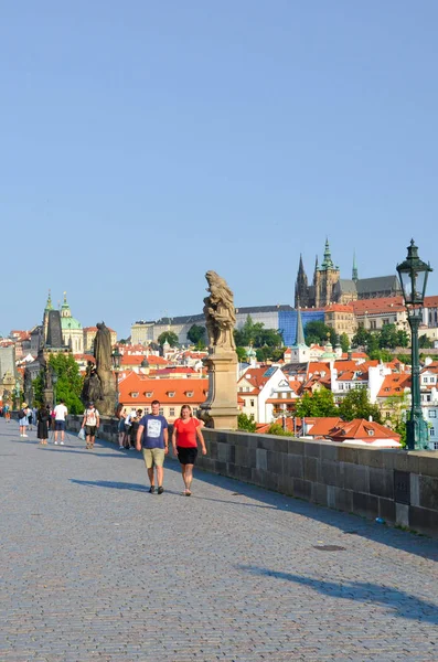 Praga, República Checa - 27 de junio de 2019: Turistas en el hermoso Puente de Carlos en el centro de la capital checa. Castillo de Praga en el fondo. Destino turístico y turístico famoso — Foto de Stock