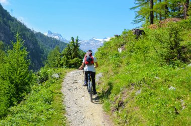 Ünlü Zermatt yakın İsviçre Alpleri güzel tepelik manzara bisiklete binen genç adam. Açık hava sporu. Bisiklet, motorcu. Alp manzarası, İsviçre. Arka planda üzerinde kar olan dağlar