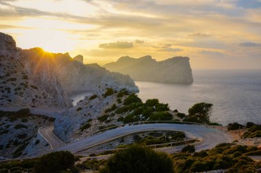 İspanyol Mallorca Cap de Formentor güzel yaz gün batımı. Güneş kayaların ve kayalıkların arkasına batıyor. Turuncu güneş. Balear Adaları, İspanya. İnanılmaz gün batımı
