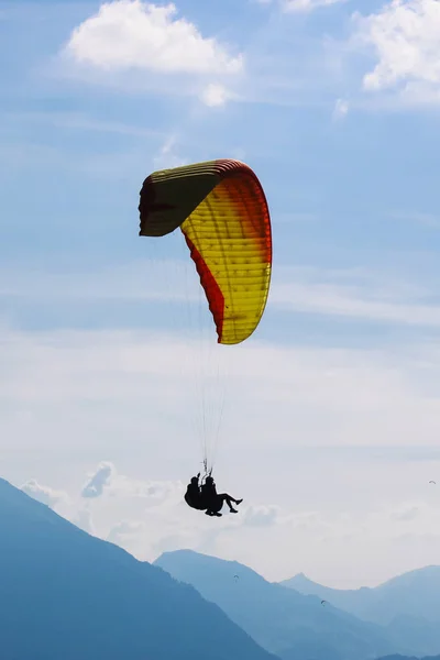 Cuadro vertical del parapente en tándem en Interlaken, Suiza. Siluetas de parapentes y montañas impresionantes. Deportes de aventura, deportes extremos. Estilo de vida, aventura. Concepto, conceptual —  Fotos de Stock