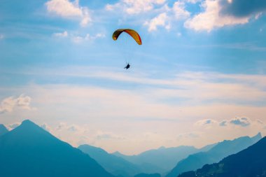 Interlaken, İsviçre'de dağların üzerinde uçan yamaç paraşütçüleri. İsviçre Alpleri Silueti. Tandem yamaç paraşütü. Şafak söktü, gün batımı. Ekstrem sporlar. Macera yaşam tarzı. Adrenalin, risk kavramı