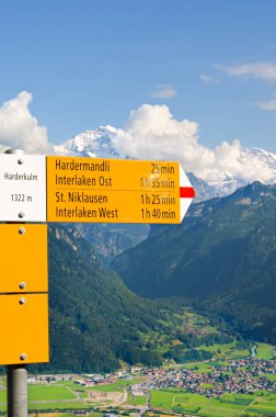 Harder Kulm, Interlaken, İsviçre'nin üstüne sarı bilgi işareti. Turist işareti mesafeleri ve yönlerini belirtir. Arka planda güzel yaz Alp manzara. İsviçre Alpleri, turizm