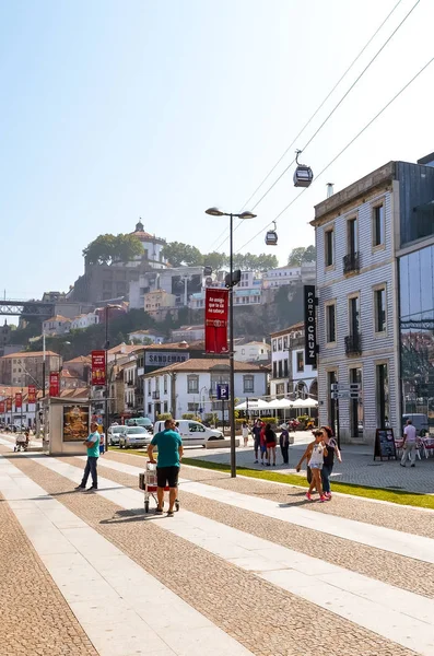 Oporto, Portugal - 31 de agosto de 2018: Turistas caminando en el paseo marítimo por el río Duero en un día soleado. El terraplén está lleno de restaurantes, bares y bodegas utilizadas para la maduración del famoso vino de Oporto. —  Fotos de Stock