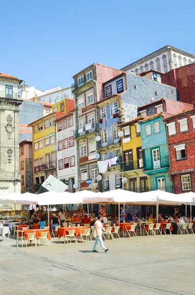 Oporto, Portugal - 31 de agosto de 2018: Gente en el paseo marítimo por el río Duero en un día soleado. El terraplén está lleno de restaurantes, bares y bodegas utilizadas para la maduración del famoso vino de Oporto. Fachadas coloridas —  Fotos de Stock