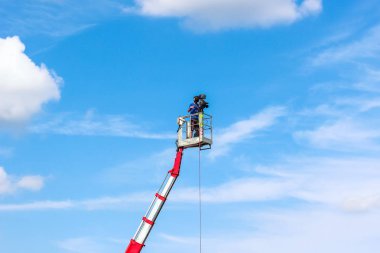 Kameraman, yerden yüksek temobil bir çalışma platformunda kayıt yapıyor. Gökyüzü ve arka planda bulutlar. Film ve video prodüksiyonu. Medya profesyonel işleri. Metin için alan kopyalayın. Meslek