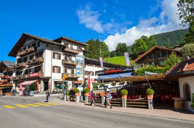 Grindelwald, İsviçre - 16 Ağustos 2019: Alp köyü Grindelwald'daki sokak. Ünlü dağlar Jungfrau, Eiger veya Monch, İsviçre Alpleri'nde yürüyüş için popüler bir başlangıç noktası. İnsanlar, şehir