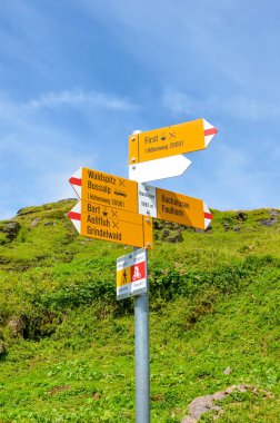 Bachlager Sarı turist işareti, İsviçre Alpleri'nde yürüyüşçüler için mesafeler ve yön veren. Grindelwald tarafından Bachalpsee giden popüler yürüyüş parkuru. Arka planda Alp akışı