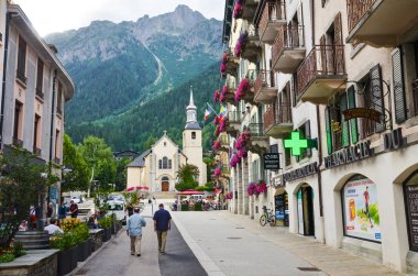 Chamonix, Fransa - 30 Temmuz 2019: Alp köyü Chamonix Sokak dükkan ve restoranlar etrafında yürüyüş insanlar ile yaz aylarında fotoğraflandı. Arka planda kilise. Fransız kayak merkezi. Turistik yer
