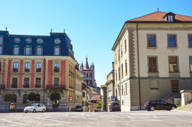 Lozan, İsviçre - 11 Ağustos 2019: Arka planda ünlü Notre Dame Katedrali ile Fransızca konuşan İsviçre şehrinin eski kenti. Tarihi binalar, yolda arabalar. Boş sokak