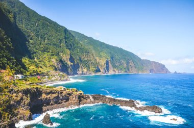 Portekiz 'in Madeira Adası' nın kuzey kıyısındaki çarpıcı uçurumlar. Dik yeşil kayalar, küçük şehir ve Seixal köyü tarafından çekilen koyu mavi deniz suyu. Turistik yerler. Atlantik Okyanusu
