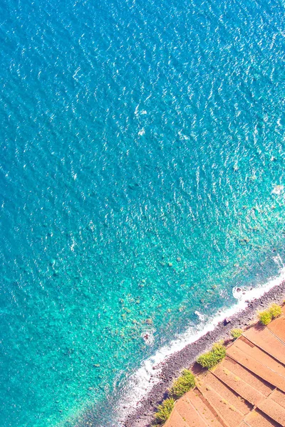 Aerial photography of the turquoise Atlantic ocean coast in Madeira, Portugal. Stone beach and adjacent fields on the southern coast of the Portuguese island. Aerial view, seascape — ストック写真