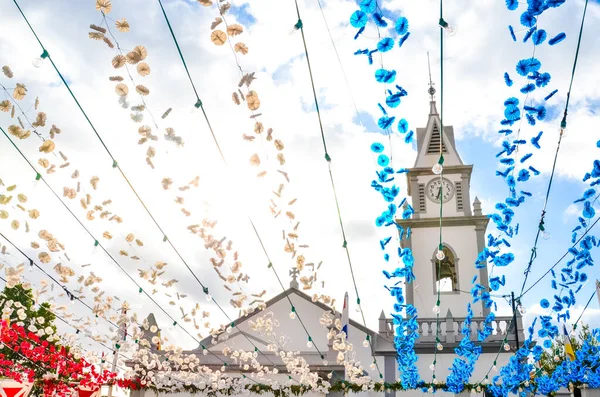 Farbenfrohe Straßendekoration, die auf der Straße in Loreto, Madeira, Portugal hängt. römisch-katholische Kirche im Hintergrund. portugiesische religiöse Festdekoration. Papierdekoration in blau, weiß und rot — Stockfoto