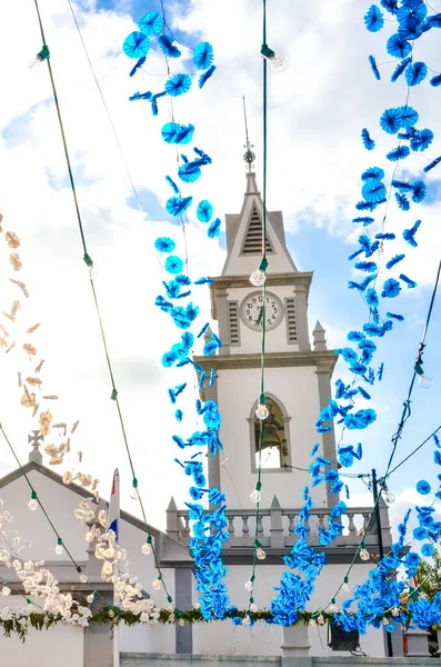 Farbenfroher Straßenschmuck hängt auf der Straße vor der römisch-katholischen Kirche in loreto, madeira, portugal. portugiesische religiöse Festdekoration. Papierblumen in blauer und weißer Farbe — Stockfoto