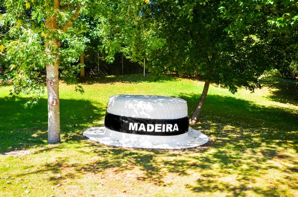 Santana, Madeira, Portugal - 24 de septiembre de 2019: Gran sombrero de paja en el parque verde. Signo blanco Madeira en el campo negro en una banda de sombreros. Sombrero de paja tradicional de Madeira. Un recuerdo típico de la isla portuguesa —  Fotos de Stock