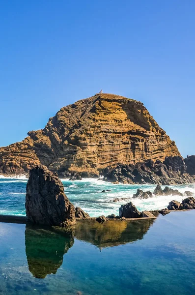 Belas piscinas naturais no oceano Atlântico, Porto Moniz, Ilha da Madeira, Portugal. Feito de rocha vulcânica, para a qual o mar flui naturalmente. Falésias ao fundo. Local turístico — Fotografia de Stock