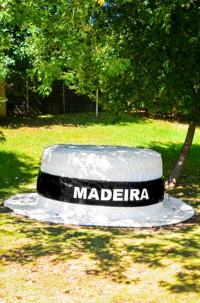 Santana, Madeira, Portugal - 24 de septiembre de 2019: Gran sombrero de paja en el parque verde. Signo blanco Madeira en el campo negro en una banda de sombreros. Tradicional sombrero de paja de Madeira. Un recuerdo típico de la isla portuguesa —  Fotos de Stock