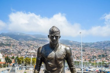 Funchal, Madeira, Portekiz - 14 Şubat 2019: Portekiz Funchal 'daki ünlü futbolcu Cristiano Ronaldo' nun Bronz Heykeli. Funchal şehri ve arka planda liman. Cr7 Müzesi 'nin bir parçası. Futbol, spor