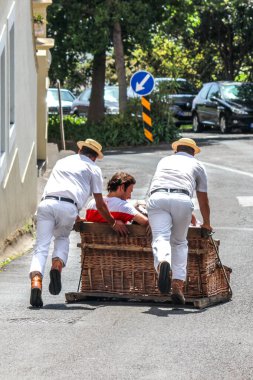 Monte, Madeira, Portekiz - Sep 14, 2019: Carreiros do Monte ile Wicker Basket Sledge turu. Funchal 'a geleneksel ulaşım aracı, şimdi bir turistik ilgi merkezi. Sürücülerle tepetaklak giden insanlar