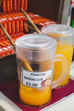 Porto da Cruz, Madeira, Portugal - Sep 24, 2019: Plastic jug with Poncha maracuja, traditional alcoholic beverage of Madeira. Typical Portuguese alcoholic drink. Sugar cane alcohol with passion fruit clipart