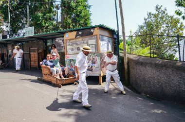 Monte, Madeira, Portekiz - 14 Şubat 2019: Wicker Basket Kızağı sürücüleri, Carreiros do Monte, turistleri yokuş aşağı sürüyorlar. Geleneksel ulaşım aracı, şimdi de turistik bir cazibe. Tipik hasır şapkalar.