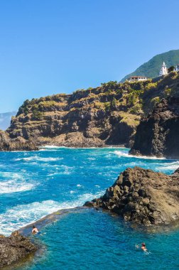Seixal, Madeira, Portekiz - 13 Şubat 2019: Atlantik okyanusunda doğal bir yüzme havuzunda yüzen çift. Denizin doğal olarak aktığı volkanik kayalardan oluşan havuzlar. Turistik yerler