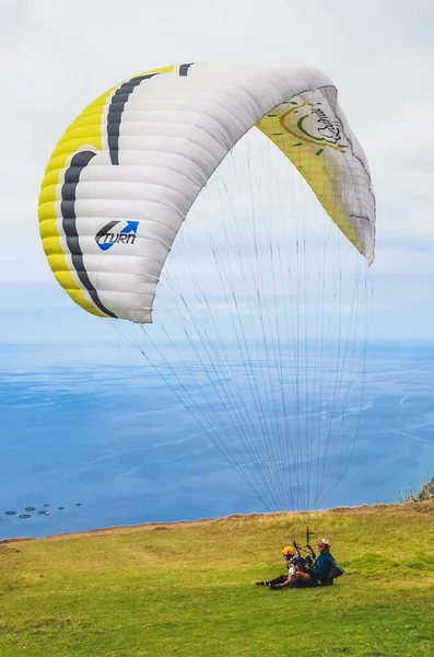 Arco da Calheta, Madeira, Portugal - Sep 16, 2019: Tandem paragliders που προσγειώνονται στα βράχια πάνω από τον Ατλαντικό ωκεανό. Το μπλε θαλασσινό νερό στο βάθος. Αλεξίπτωτο, extreme sports — Φωτογραφία Αρχείου