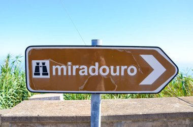 Portekizce miradouro yazan eski, kısmen hasarlı kahverengi turist tabelası. Bilgi işaretleri. İşaretleme sistemi. Dürbün sembollü ok. Çeviri: miradouro, bakış açısı demek.
