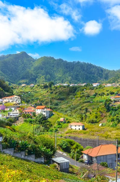 Aldeia pitoresca Porto da Cruz na Madeira, Portugal. Cidade pequena cercada por colinas verdes. Edifícios rurais numa colina. Área remota da paisagem portuguesa. Bela paisagem — Fotografia de Stock