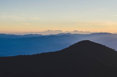 İlkbahar gün batımı dağların üzerinden. tepeler haddeleme üzerinde tarım alanları ile güzel bir kırsal manzara