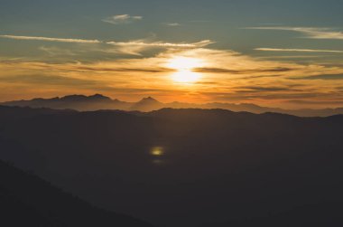 İlkbahar gün batımı dağların üzerinden. tepeler haddeleme üzerinde tarım alanları ile güzel bir kırsal manzara