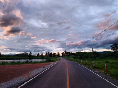 yaz günü mavi gökyüzünde beyaz bulutlar altında yeşil çim alan üzerinden tepeye kadar yol. Yol gezisi seyahat konsepti.