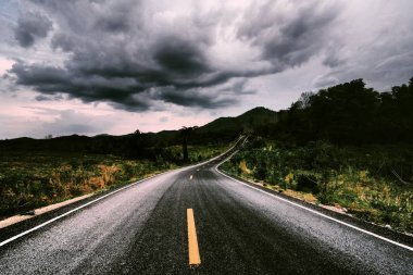 yaz günü mavi gökyüzünde beyaz bulutlar altında yeşil çim alan üzerinden tepeye kadar yol. Yol gezisi seyahat konsepti.