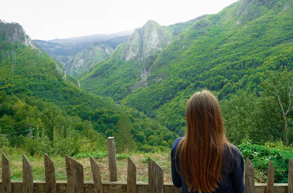 Girl looks into the distance. The mountains are covered with greenery. Montenegro