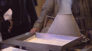 Sokak satıcısı satış ve taze kestane kavurma, kavurma duman yakın çekim görüntüleri, tuz, ve eller. Baixa Chiado, Lizbon, Portekiz