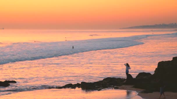 Hombre caminando en marea baja, cielo atardecer reflexiones sobre el agua en la playa de Carcavelos — Vídeos de Stock