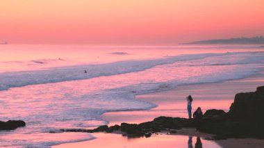 Adam düşük gelgit yürüyüş, Carcavelos plajda su üzerinde günbatımı gökyüzü yansımaları