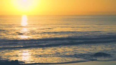 Su yansımaları ile derin sarı günbatımı sırasında Dalgalar, Carcavelos plaj, Portekiz