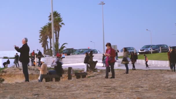 Sziluettek az emberek képek fotózás napnyugtakor, Carcavelos Beach, Portugália. — Stock videók