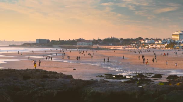 Rallentatore di persone sulla spiaggia di Carcavelos durante il tramonto giallo intenso, Portogallo — Video Stock