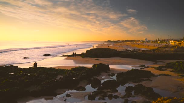 Personas en la bahía rocosa en la playa durante la puesta del sol de oro, Portugal — Vídeos de Stock