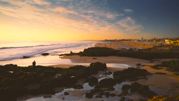 Pessoas na baía rochosa na praia durante o pôr-do-sol dourado, Portugal — Vídeo de Stock