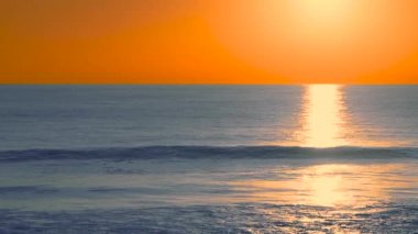Su yansımaları ile derin sarı günbatımı sırasında Dalgalar, Carcavelos plaj, Portekiz