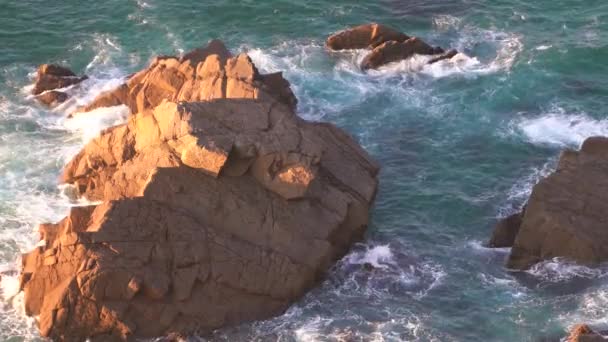 Ondas quebrando em câmera lenta contra duas pedras enormes na água — Vídeo de Stock