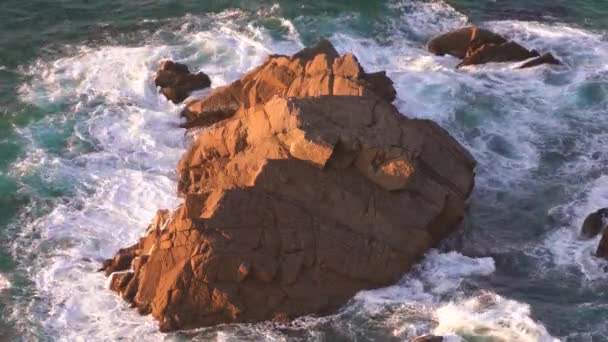 Olas rompiendo en cámara lenta contra una enorme roca en el agua — Vídeo de stock